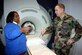Mary Perkins, MRI technician, explains to Col. Rick Martin, 305th Air Mobility Wing commander, how the MRI machine in the new trailer works during a recent tour at the medical clinic here. Colonel Martin participated in a demonstration of how the MRI machine works, going halfway into the machine, with assistance from Ms. Perkins. U.S. Air Force photo by Airman Rebekah Phy