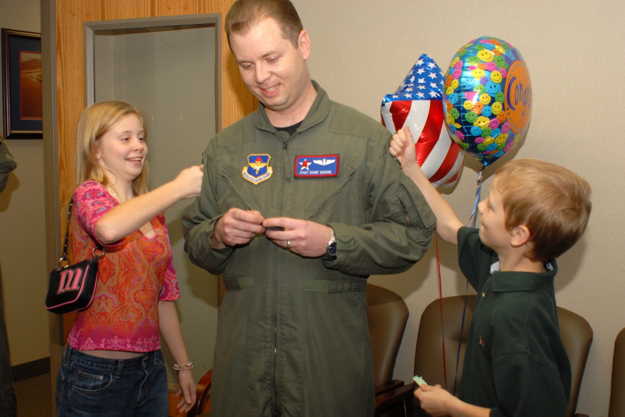 Newly promoted Tech. Sgt. Dane Moore, 714th Training Squadron, braces himself for punches from his daughter, Morgan, and son, Jack, during his STEP promotion Dec. 18. The Stripes To Exceptional Performers program allows the 314th Airlift Wing commander to promote individuals who have gone above and beyond in the line of duty. (Photo by Airman 1st Class Christine Clark)