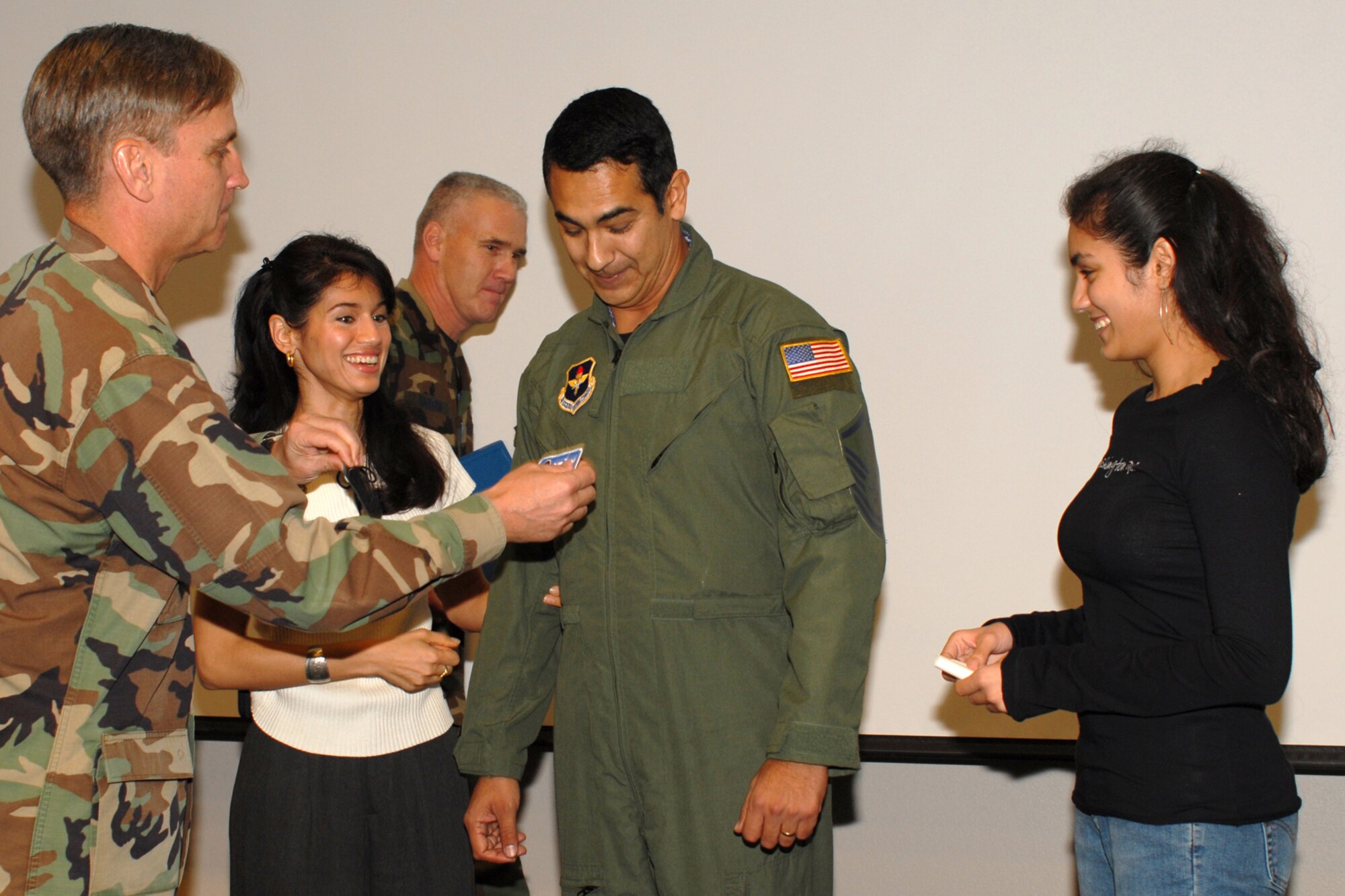 Brig. Gen. Kip Self, (left) 314th Airlift Wing commander, installs a new flight patch on newly promoted Master Sgt. Richard Pinedo, 62nd Airlift Squadron, during his STEP promotion Dec. 18, as his wife, Sarah, and daughter, Mari, look on. The Stripes To Exceptional Performers program allows the 314th Airlift Wing commander to promote individuals who have gone above and beyond in the line of duty. (Photo by Airman 1st Class Christine Clark)