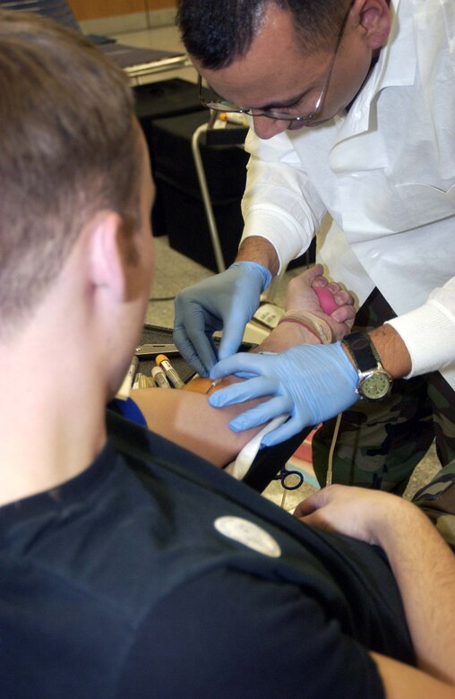 Petty Officer 2nd Class Brian King, from the U.S. Army Europe Blood Donor Center, inserts the needle into the arm of Senior Airman Christopher O'Dai, 723rd Air Mobility Squadron counter measures technician, during the 723rd AMS blood drive Dec. 13 at the 64th Replacement Battalion in the Ramstein Passenger Terminal. 
