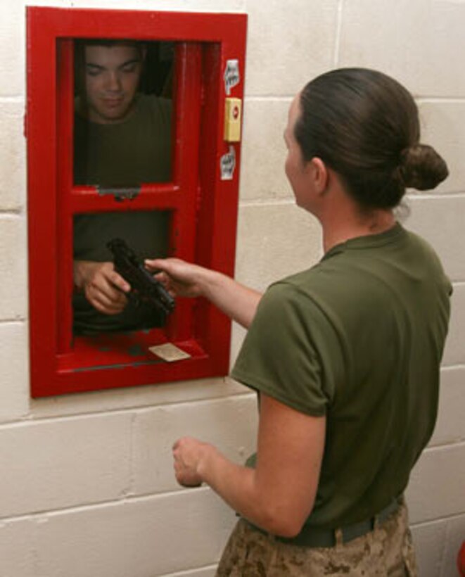 MARINE CORPS BASE CAMP H.M. SMITH, Hawaii --  Capt. Melinda Cousins (right), administration officer, MARFORPAC, returns an M-9 pistol to the armory after a thorough cleaning. (Official USMC Photo by Lance Cpl. Ethan Hoaldridge)