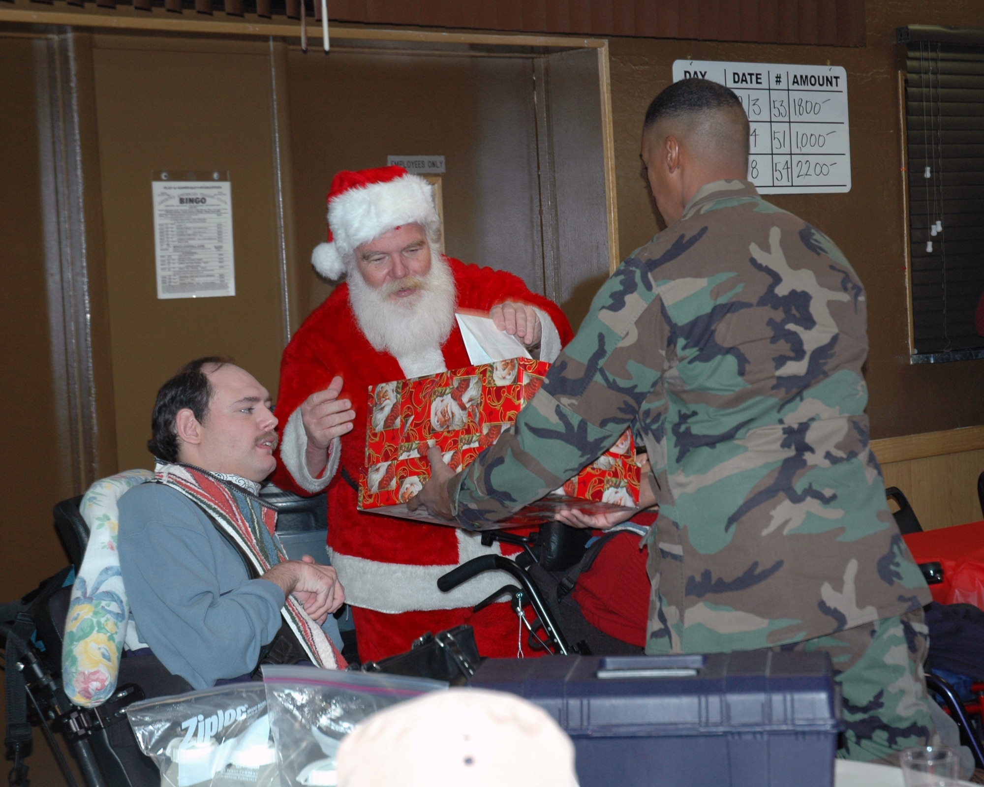 Second Lt. Derrick Young, 944th Fighter Wing military equal opportunity, hands a present to Santa during the wing's annual holiday kick off celebration at the American Italian Club in Phoenix on Dec. 2. Thirteen members of the wing visited with about 200 clients of the Valley of the Sun Habilitation School, an event the wing has participated in for more than 20 years. (U.S. Air Force photo/Tech. Sgt. Barbara Plante)