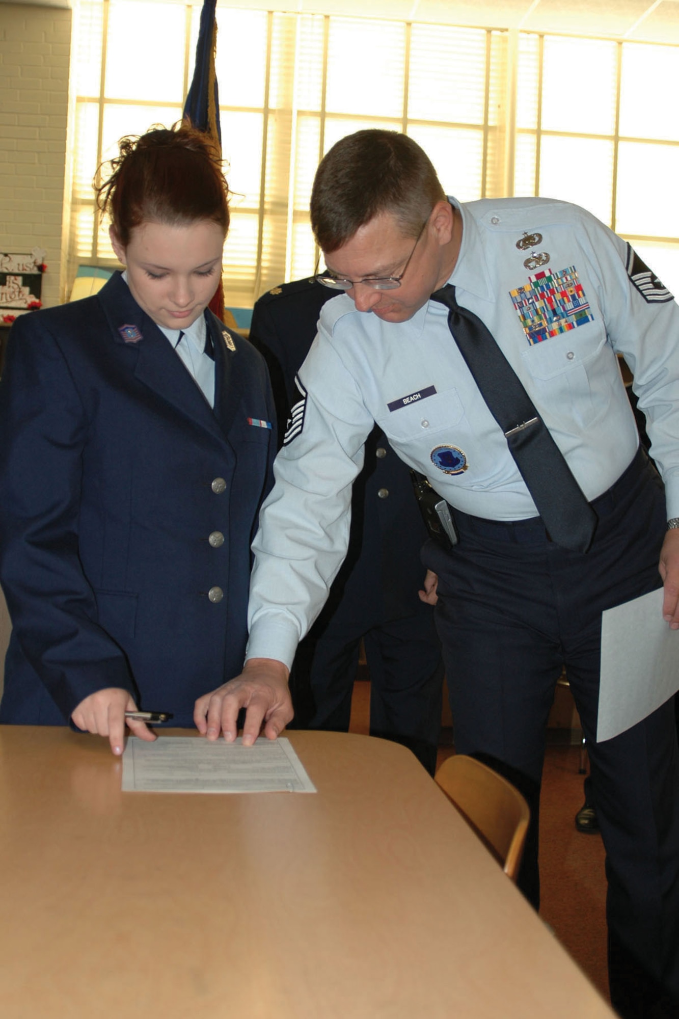 Master Sgt. David Beach, 917th Wing recruiter (right), shows Air Force Reserve Recruit Brittany Duelm where to sign her enlistment paperwork Tuesday, Dec. 5, at Bossier High School. Brittany's father, William, is a retired Air Force master sergeant, and her sister, Tiffany, served four years in the Air Force. (U.S. Air Force photo/Tech. Sgt. Sherri Savant)