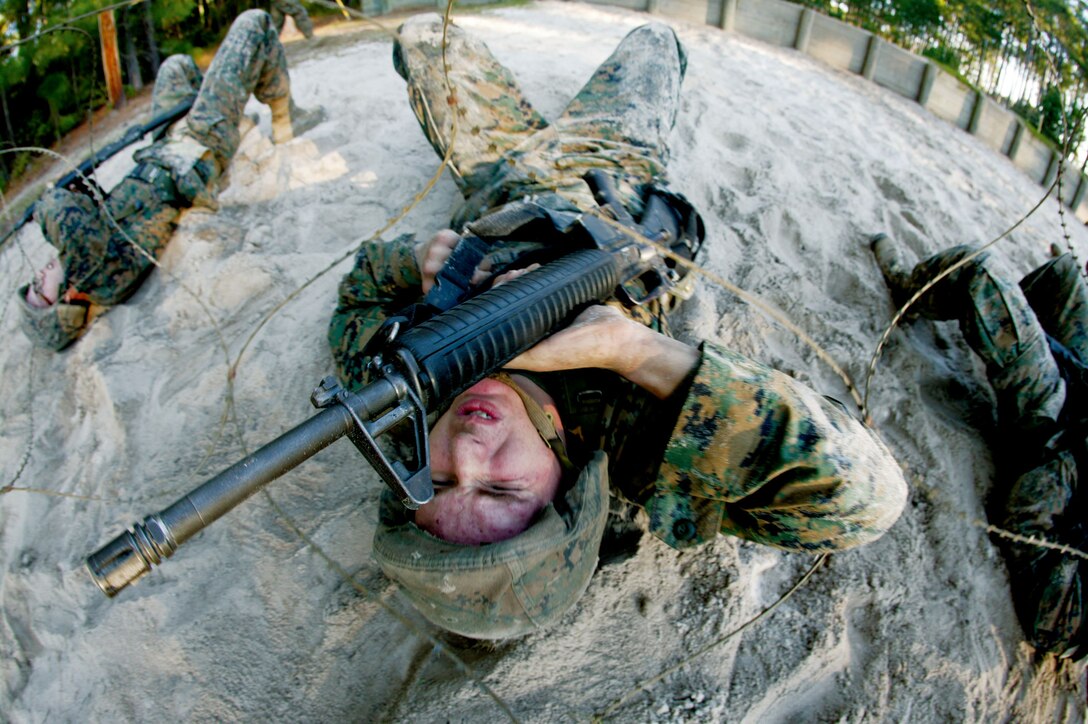 Rct. Ryan Bell, from Golf Company's Platoon 2109, lifts the barbed wire above his body using his M16-A2 Service Rifle during the Basic Warrior Training's Day Walk Course Nov. 6. The course is designed to show recruits certain elements they may see in a combat-like environment.
