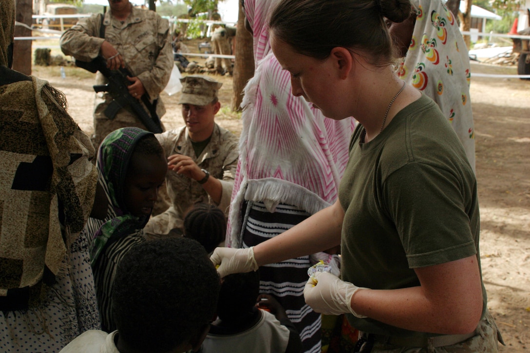 Cpl. Brandy N. Campbell of Combat Logistics Battalion 26, 26th Marine Expeditionary Unit, hands candy to a Kenyan child awaiting medical attention during a bilateral Medical Civil Assistance Project in Bargoni, Kenya, March 7, 2007.  The 26th MEU conducted bilateral training and community relations projects with the Kenyan armed forces during Exercise Edged Mallet '07.