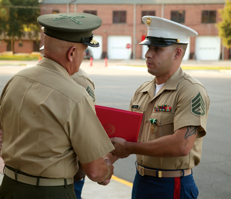 Brig. Gen. Paul E. Lefebvre, commanding general, MCRD Parris Island/Eastern Recruiting Region, presents Staff Sgt. Valentino Mendoza with the Navy and Marine Corps Commendation Medal citation.