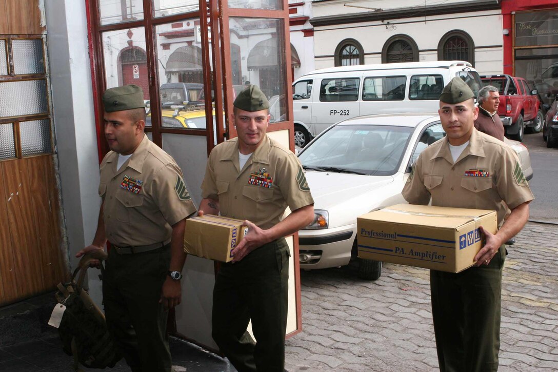 IQUIQUE, Chile - Staff Sgt. James Palmer, regimental radio chief for 24th Marine Regiment of Kansas City, Mo.; Staff Sgt. David Luna, force protection chief for Special Purpose Marine Air- Ground Task Force 24; and Sgt. Daniel Garcia, a radio operator with 24th Marine Regiment; enter the Sargento Aldea Fire Co. carrying parts to an amplified sound system. Marines of SPMAGTF 24 teamed up with Chilean Marines of DIM Lynch to present the system to the firehouse. SPMAGTF 24 is currently supporting Partnership of the Americas 2007, an annual exercise that enhances regional security and cooperation among nations of the Western Hemisphere.