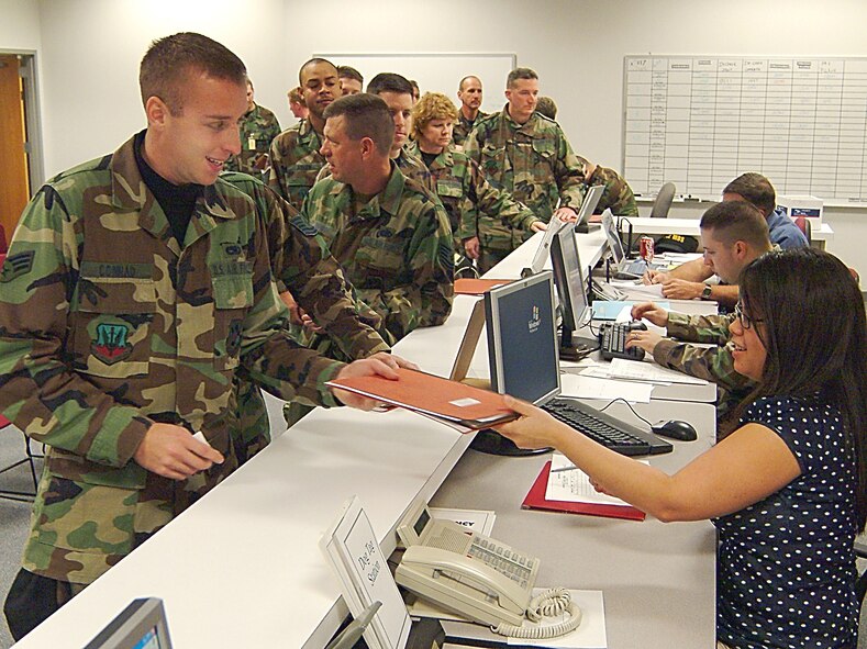 WHITEMAN AFB, Mo. -- Air Force reservist, Senior Airman Bernie Conrad, 442nd Aircraft Maintenance Squadron, hands his personnel readiness folder to Charlynne Rojas, a civilian contractor with Whiteman's 509th Mission Support Squadron, for review as he works his way through the various stations of the base's deployment processing center. Airman Conrad, and nearly 300 fellow reservists, helped flex the 442nd Fighter Wing's deployment muscles during an exercise, Jan. 5-7, which focused on the Wing's readiness to deploy in support of wartime taskings. (US Air Force photo / Master Sgt. Bill Huntington)