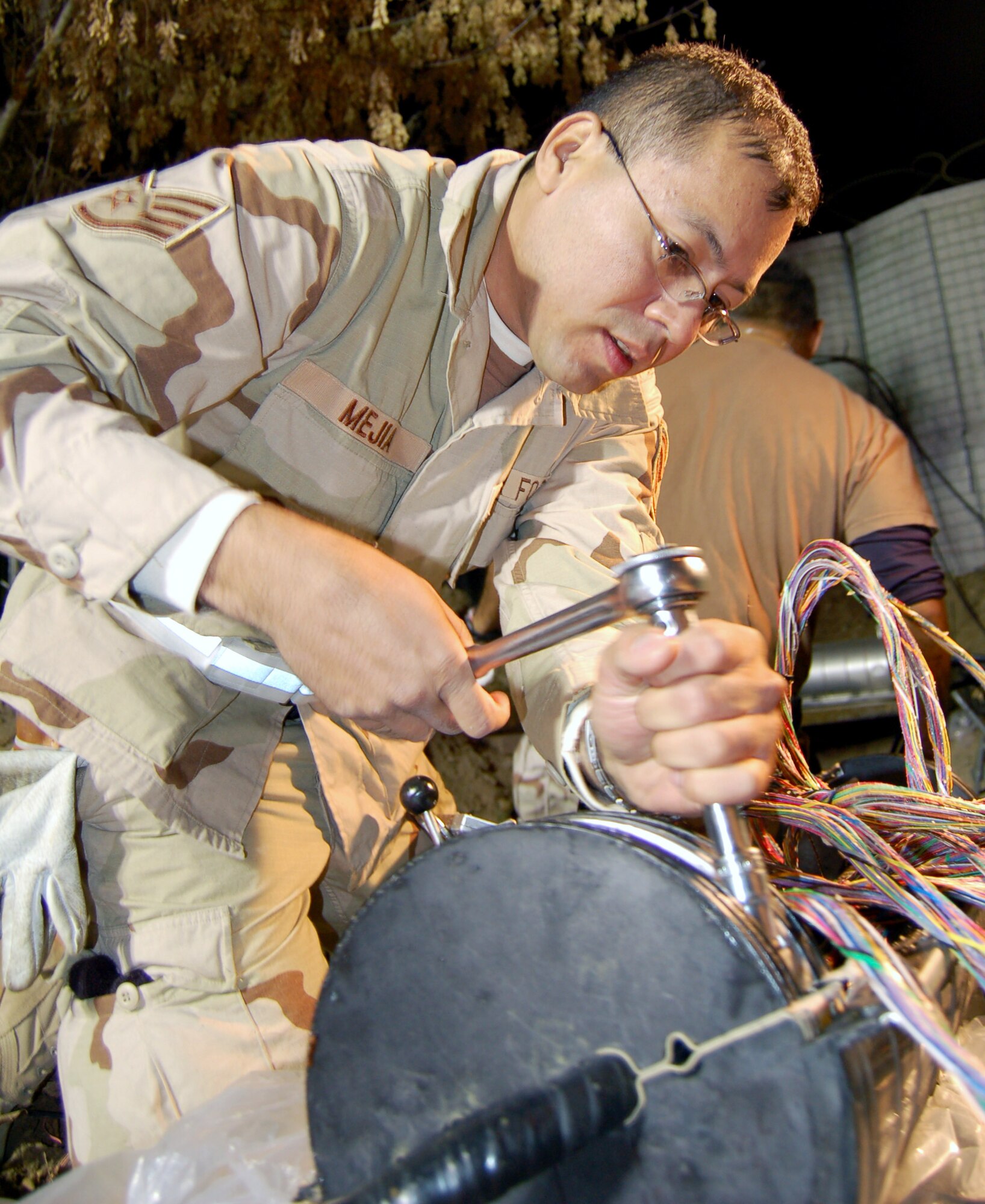 Staff Sgt. Mario Mejia loosens a telephone line splice case in order to feed the line cables into the ends of the case at Manas Air Base, Kyrgyzstan. Sergeant Mejia is one of the five engineering and installation team members helping the 376th Expeditionary Communications Squadron transfer all DSN numbers to the new telephone switch. Sergeant Mejia is deployed from the 272nd Engineering and Installation Squadron at Laporte, Texas. (U.S. Air Force photo/Master Sgt. Mitch Gettle)