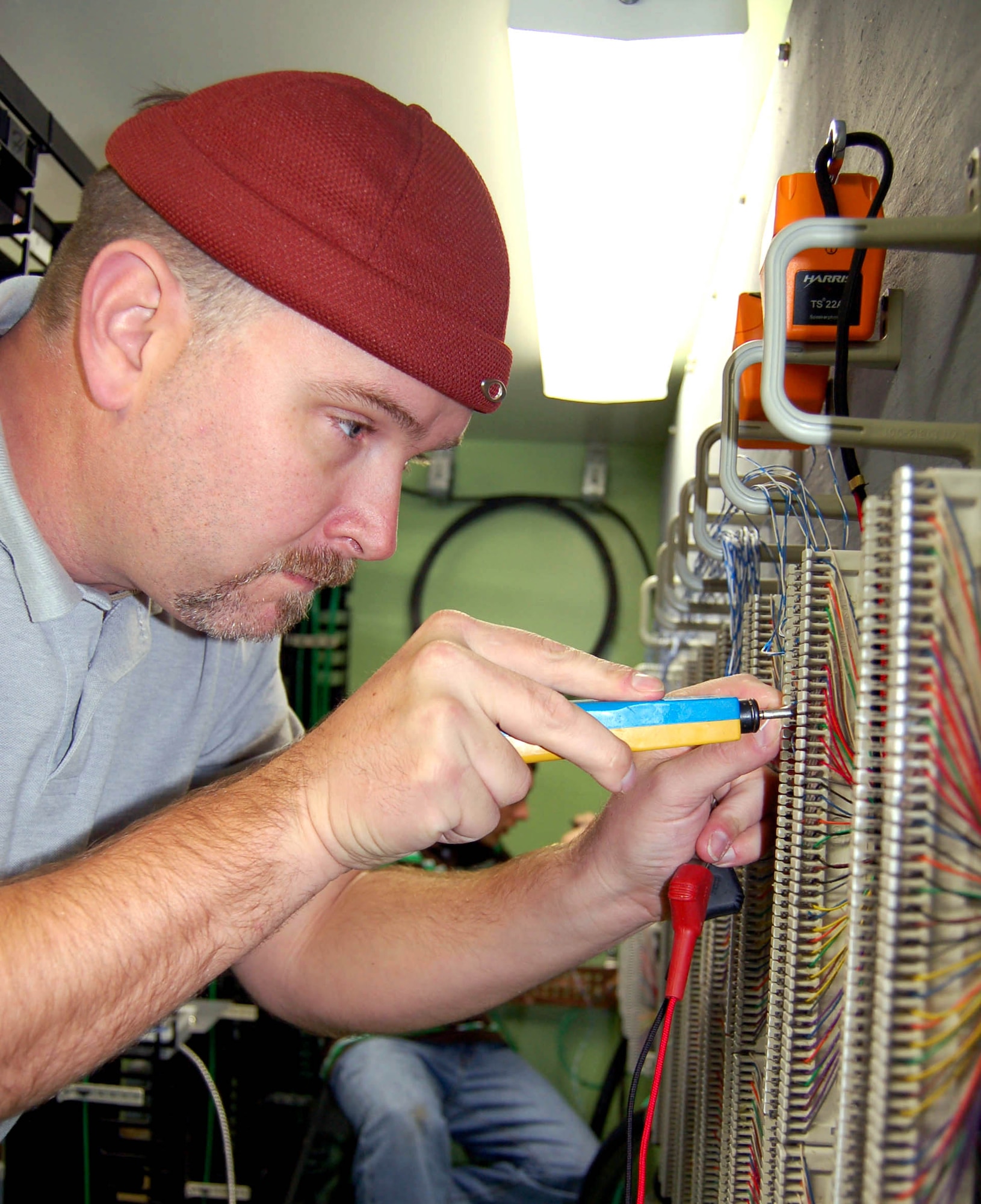 David Grace, a 376th Expeditionary Communications Squadron contractor, uses a tool to connect phone lines from one line block to another. The tool terminates telephone line cuts by securing the copper to the phone block. (U.S. Air Force photo/Master Sgt. Mitch Gettle)