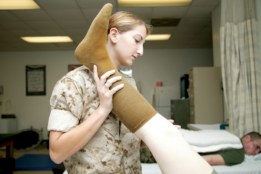 Navy Seaman Apprentice Jennifer Nuehring, a corpsmen at the Parris Island Branch Medical Clinic's Physical Therapy Department, assists a patient in streching exercises  as part of her range of motion training Oct. 9.