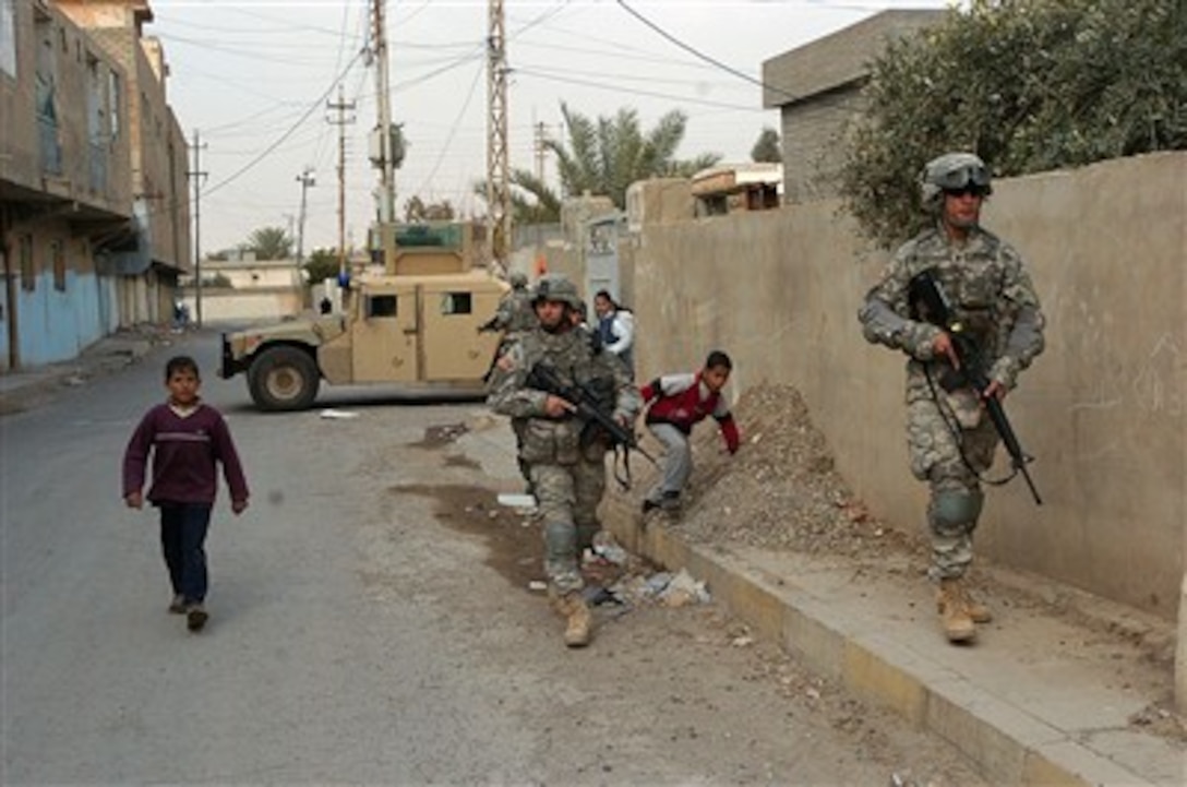 Neighborhood boys follow U.S. Army Staff Sgt. John Comito (left) and Spc. Serrano as they conduct a foot patrol in Tikrit, Iraq, on Dec. 27, 2006.  