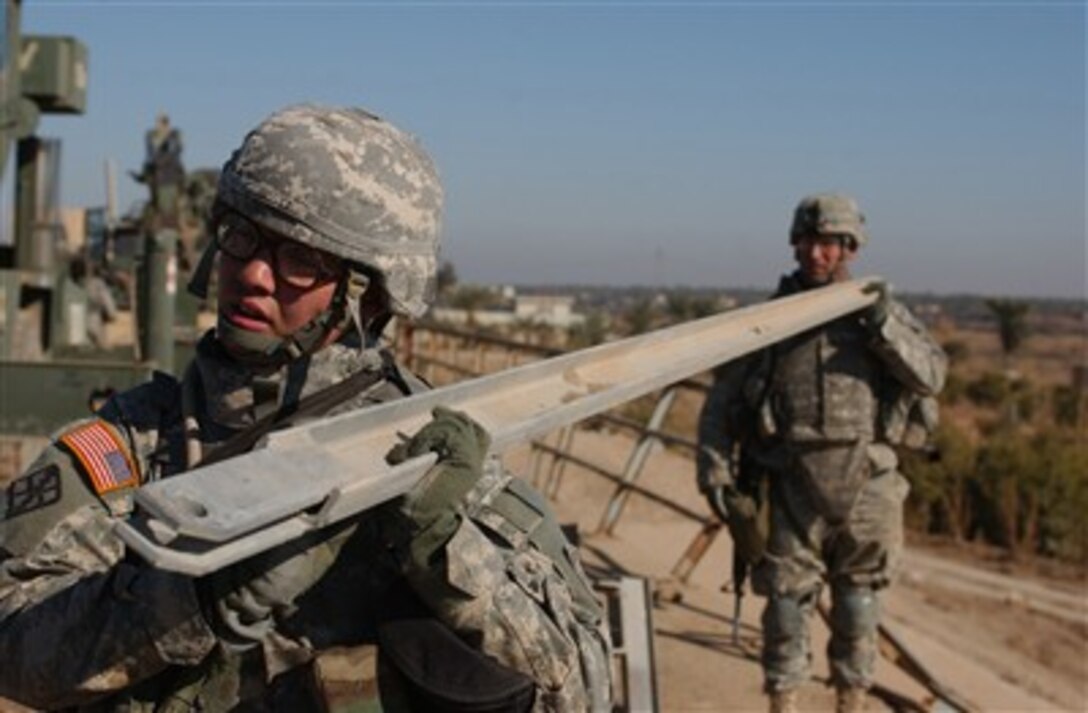 Soldiers from the U.S. Army's 502nd Engineer Company carry beams as they disassemble a bridge near Taji, Iraq, on Jan. 3, 2007.   The bridge is being disassembled to deter insurgents from transporting weapons across it.  