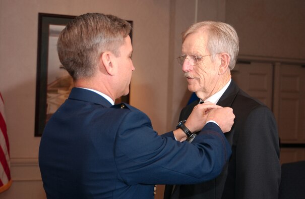 Brig. Gen. Kip Self, 314th Airlift Wing commander, pins the Outstanding Civilian Service Award device on Dan Daniel, 314th Airlift Wing Equal Opportunity Program Manager, during his retirement ceremony Jan. 5. Mr. Daniel is a retired command pilot and has faithfully served the nation more than 53 years.