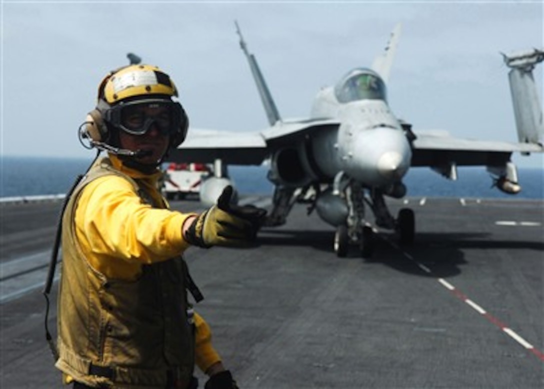 A U.S. Navy plane director directs the pilot of an F/A-18 Hornet to the next director aboard the Nimitz-class aircraft carrier USS Dwight D. Eisenhower (CVN 69) on Jan. 8, 2007.  The Eisenhower and embarked Carrier Air Wing 7 are on deployment in support of maritime security operations.  