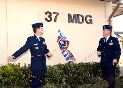 Brig. Gen. Darrell Jones, then the 37th Training Wing commander, and Col. Tim Halligan, then the commander of the newly reactivated 37th Medical Group, unveil the group's abbreviation on its headquarters building across Biggs Avenue from the Warhawk Fitness Center. General Jones led the Dec. 22, 2006, ceremony to reactivate the group, the first medical assets under direct control of the 37th TRW since Wilford Hall Medical Center was completed in 1957. (USAF photo by Robbin Cresswell)