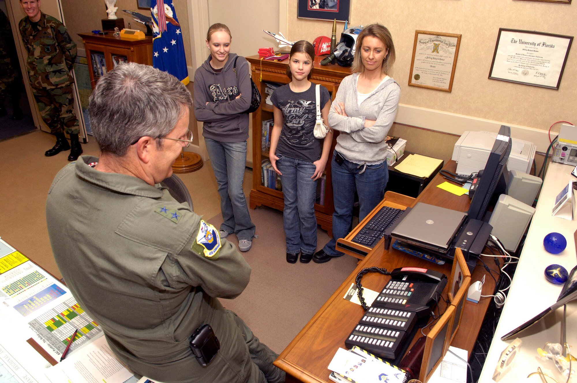 Maj. Gen. Jeffrey Riemer, program executive officer for weapons and Air Armament Center commander, congratulates Tech. Sgt. Dennis Barnett, 96th Security Forces Squadron, on his Stripes For Exeptional Performers promotion Jan. 9 while his wife and daughters look on. Sergeant Barnett is currently deployed.
