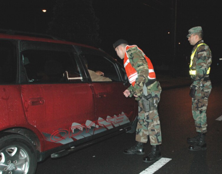YOKOTA AIR BASE, Japan -- Airman 1st Class Edward Grant and Staff Sgt. Kenneth Lewis, 374th Security Forces Squadron, conduct a random vehicle check on base here Saturday. (U.S. Air Force photo/ Staff Sgt. Ruth Curfman) 
