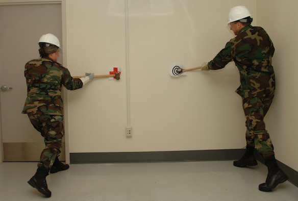 Colonel Barbara Jefts, 92nd Medical Group commander, and Col. Scott Hanson, 92nd Air Refueling Wing commander, swing sledgehammers at the base clinic Jan. 5 to kick off the construction project and dedicate the new pharmacy expansion.