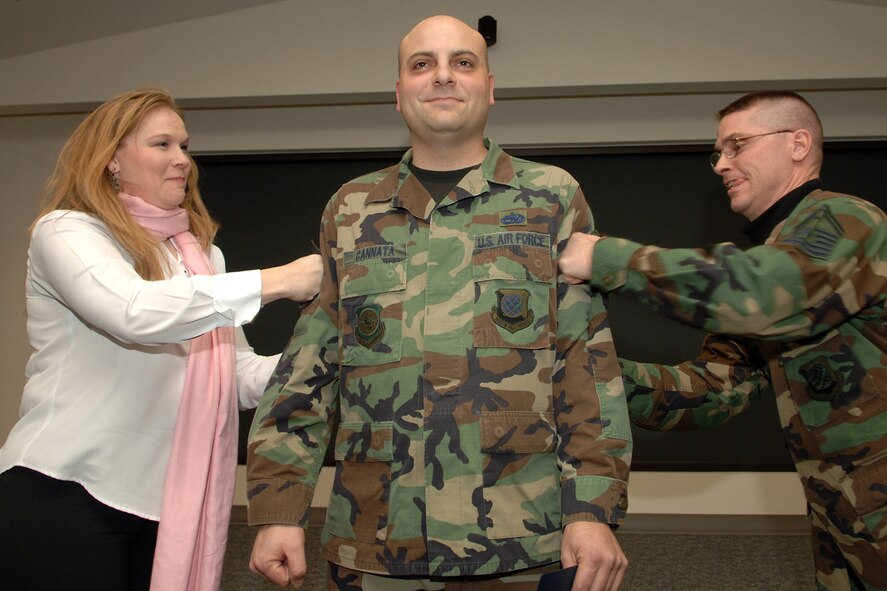 Katherine Cannata, wife of now Master Sgt.  George Cannata, tacks on her husband?s new stripes along with Senior Master Sgt. Daniel North, 92nd Aircraft Maintenance Squadron first sergeant. Sergeant Cannata, 92nd AMXS maintenance operations exec, was STEP promoted to the rank of master sergeant Dec. 15.
