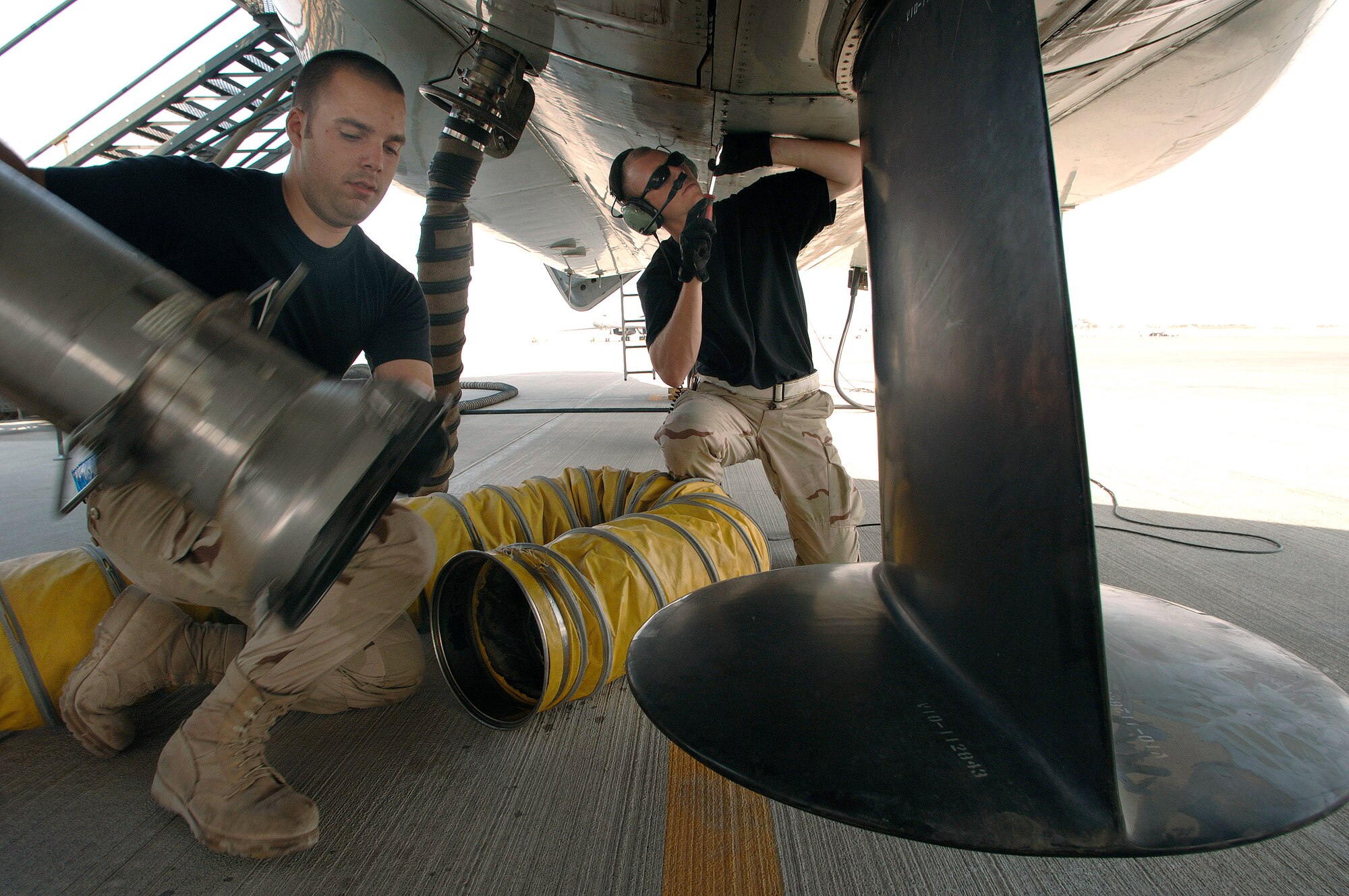 Senior Airman Matthew Campbell and Airman 1st Class Jonathan Campana remove air conditioning hoses from an RC-135 Rivet Joint reconnaissance aircraft prior to its departure for a mission over Southwest Asia.  The air conditioning system helps maintain cool temperatures for the extensive electronics onboard the plane during the lengthy start up process. Both Airmen are crew chiefs deployed from the 55th Aircraft Maintenance Squadron, Offutt Air Force Base, Neb. (U.S. Air Force photo/Master Sgt. Scott Wagers)