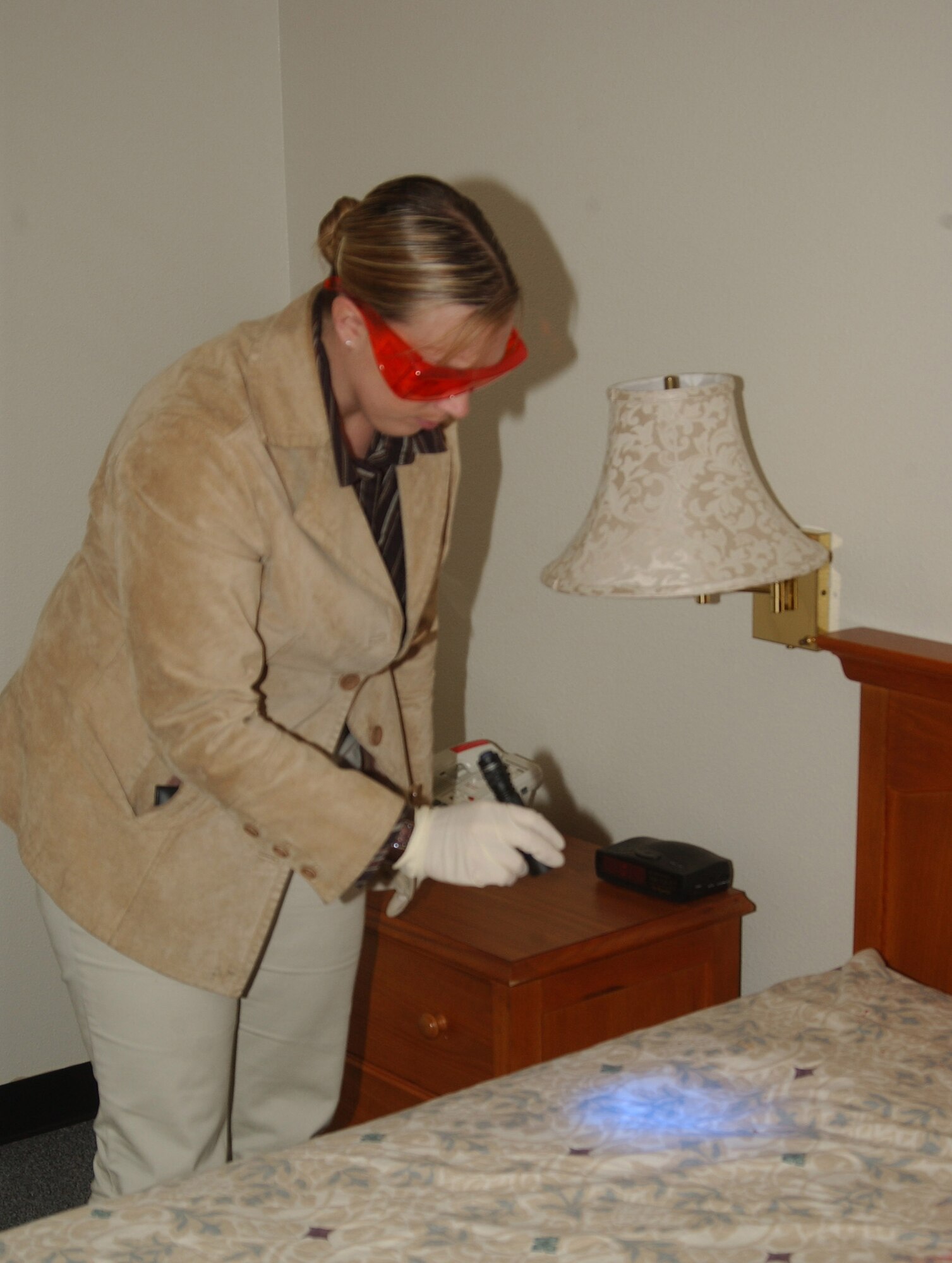 MCCHORD AIR FORCE BASE, Wash. -- Special Agent Trisha Krull uses a blacklight to find evidence at the simulated crime scene. (U.S. Air Force Photo/Randy White)         
        