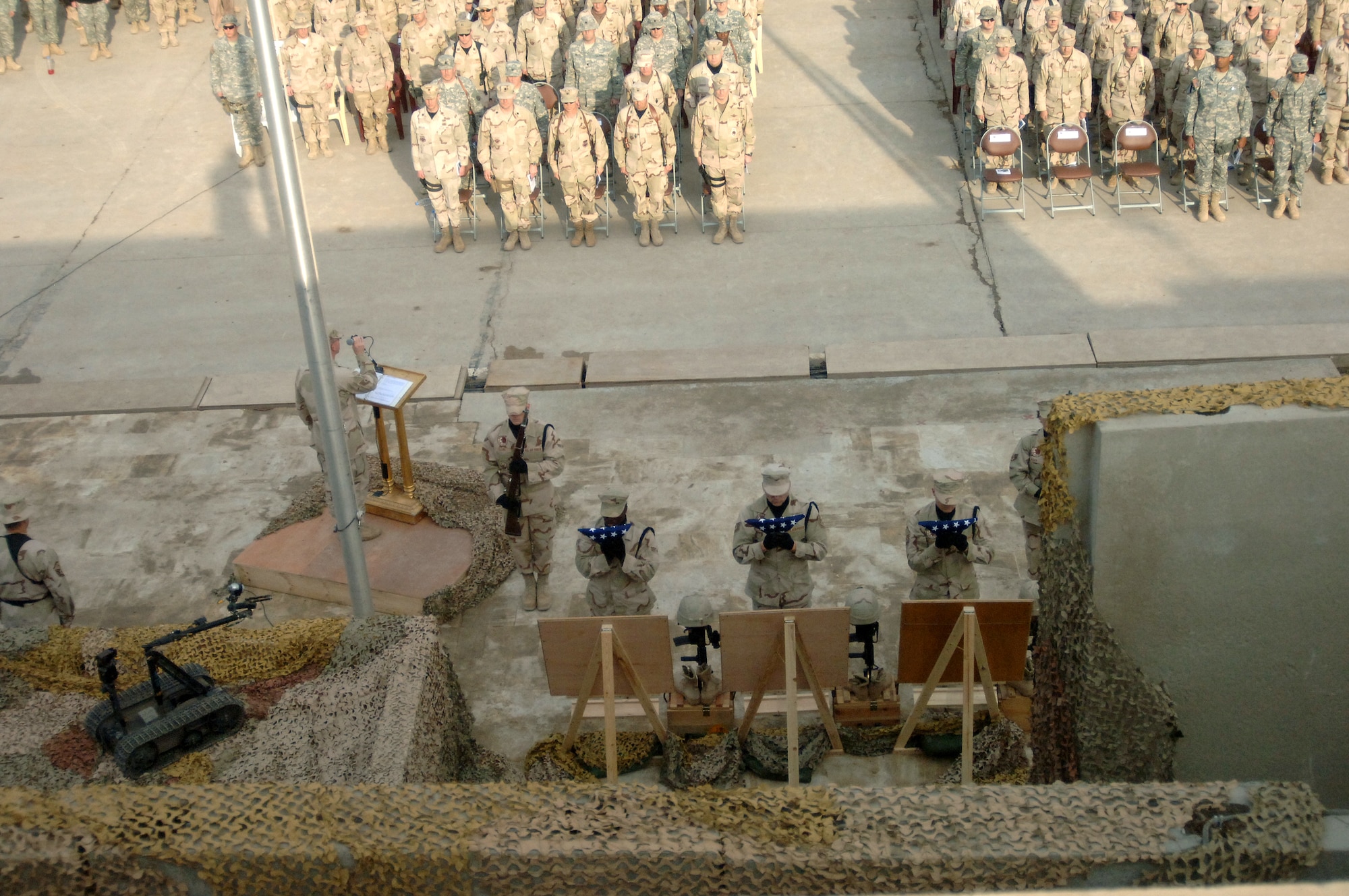 Members of the 447th Air Expeditionary Group at Sather Air Base, Iraq, honor three Airmen Jan. 10 who were killed in the line of duty Jan. 7 when a vehicle-borne improvised explosive device they were investigating detonated.  Base honor guard Airmen place flags under photos of the three fallen heroes.  (U.S. Air Force Photo/Staff Sgt. Scott McNabb)
