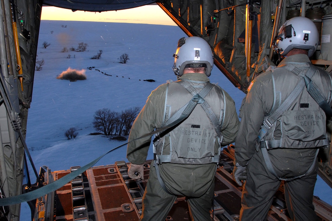 Loadmasters from the Wyoming Air National Guard watch a one-ton hay bale land near a herd of cows during an emergency feeding mission Jan. 3 caused by a snowstorm that hit the area in southeastern Colorado. (U.S. Air Force photo/Senior Master Sgt. John Rohrer)