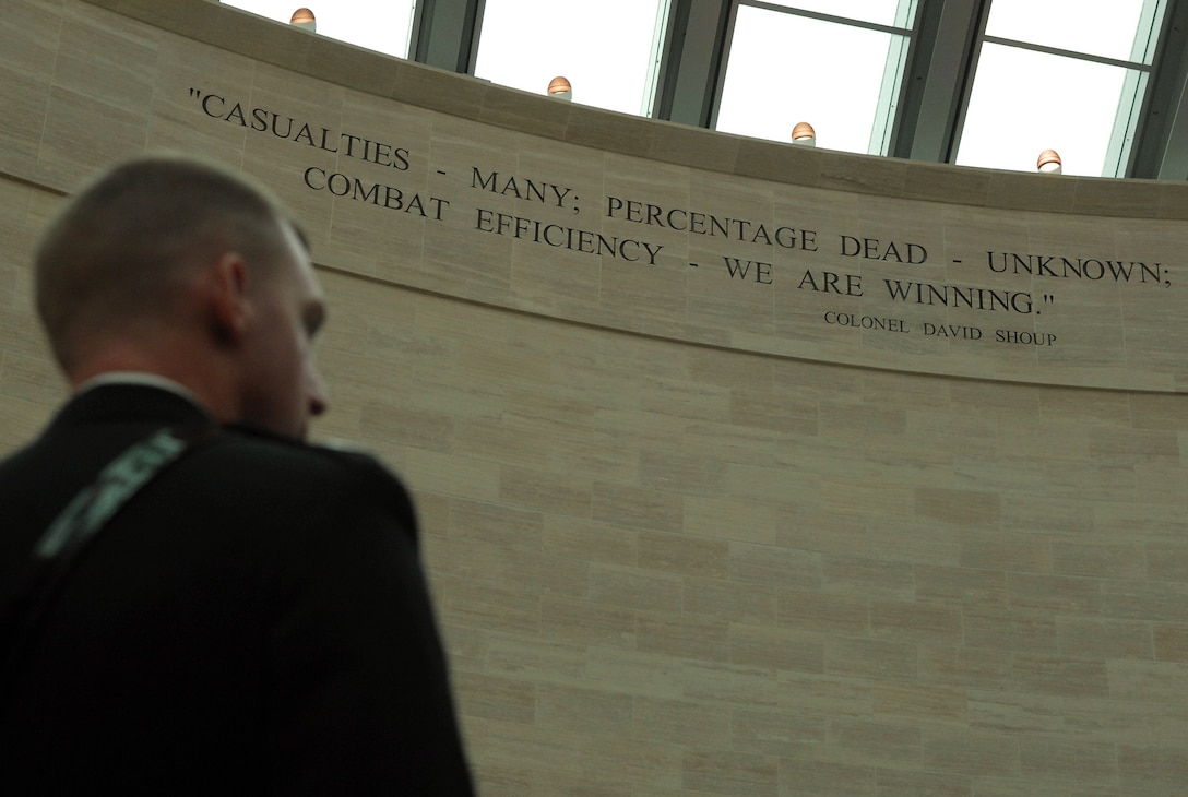 A Marine stands beneath a quote by Medal of Honor recipient Marine Col. David Shoup, engraved on a wall in “The Leatherneck Gallery” of the National Museum of the Marine Corps, in Quantico, Va., Jan. 12, 2007. During the World War II battle for the Pacific island of Tarawa in 1943, Shoup said, “Casualties – many: percentage dead – unknown: combat efficiency – we are winning.”