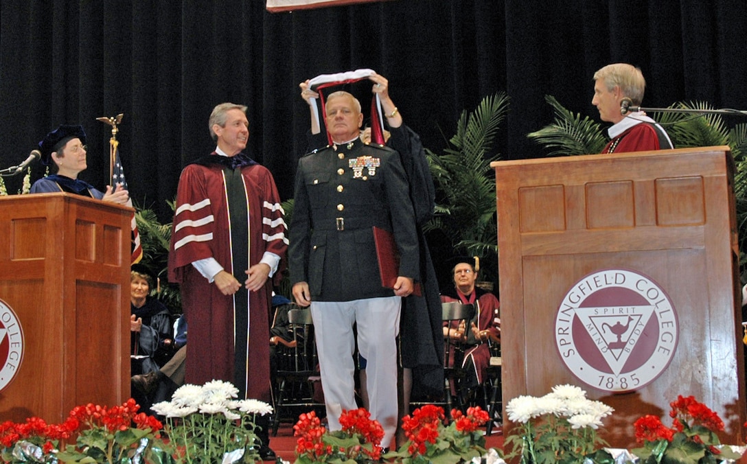 Professor Mimi Murray Grand Marshal of commencement ceremonies places the doctoral hood upon Brig. Gen. Paul E. Lefebvre. Jean A. Wyld vice president for academic affairs, James E. Walsh, Chair of Springfield College's board of trustees and Dr. Richard Flynn president of Springfield College look on. Military service is a service organization at heart said Debbie B. Lefebvre, wife of Lefebvre. This honor is an acknowledgement to the sacrifices made by all the young men and women serving in the Marines.