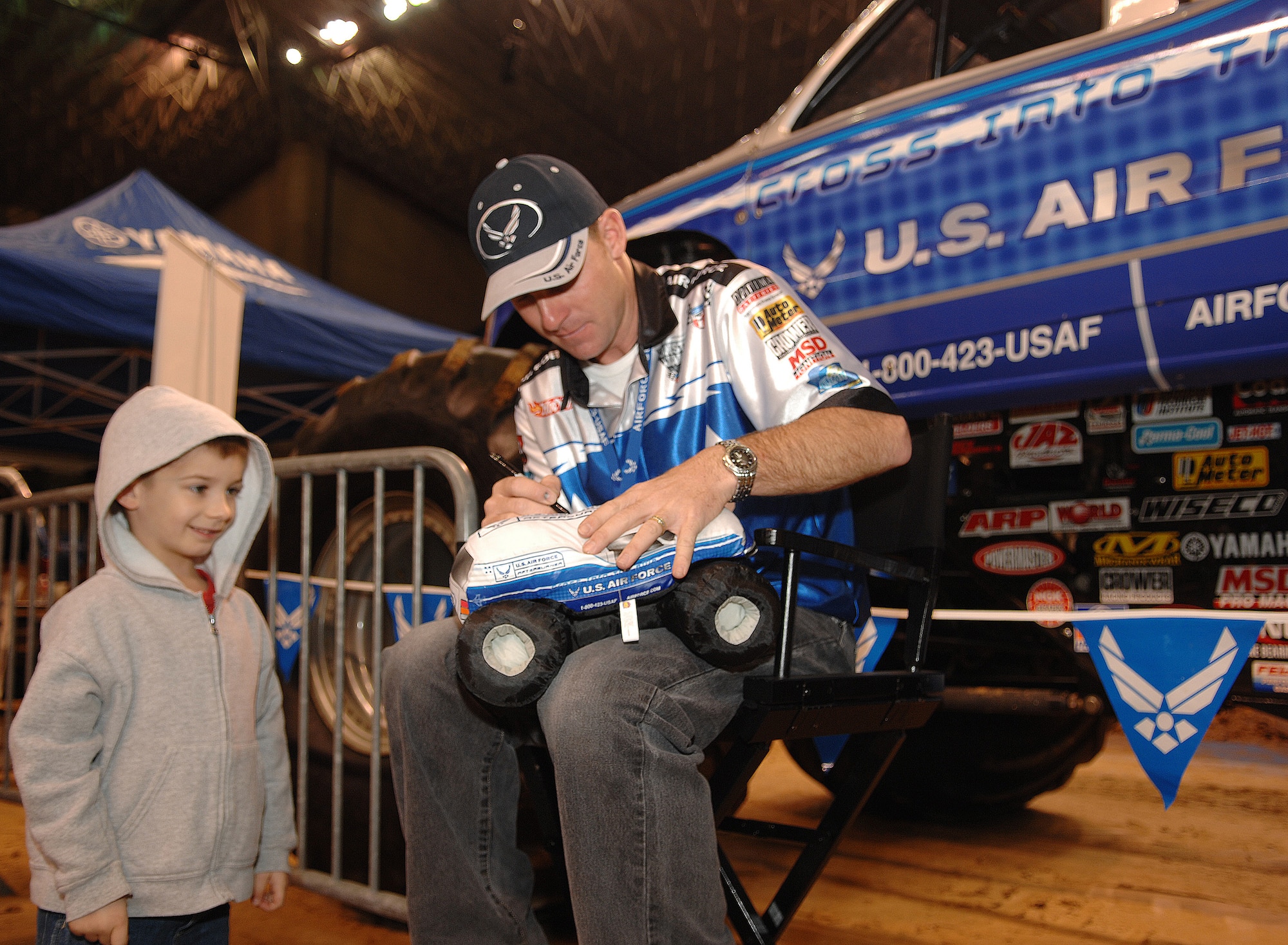 Damon Bradshaw, driver of the Air Force sponsored monster truck Afterburner, autographs a stuffed version of Afterburner for Ethan VanDevender during the Party in the Pits prior to the start of the 2007 Monster Jam in San Antonio, Texas, January 13, 2007. Ethan is the son of Tech. Sgt. Bryce VanDevender, 37th Security Forces Squadron, Lackland AFB, TX. (US Air Force photo/Master Sgt. Scott Reed)