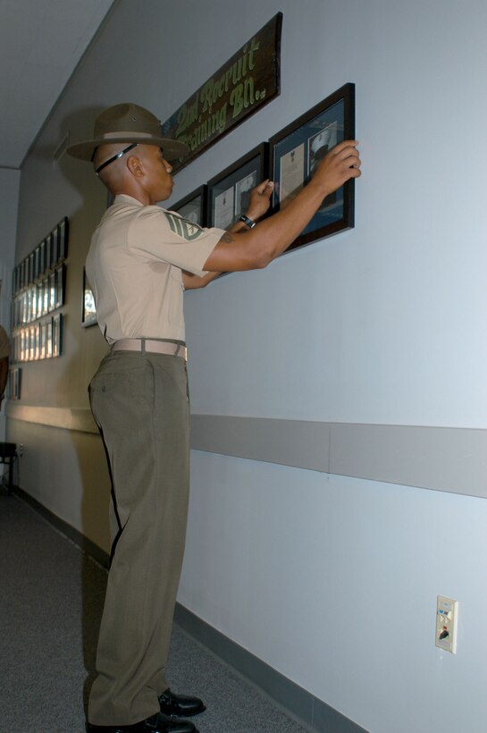 Staff Sgt. Antonio Hairston the 2nd Recruit Training Battalion drill master hangs Cpl. Jason Dunham's photo and Medal of Honor citation on the 2nd RTBn.'s Wall of Heroes. Dunham completed recruit training in Golf Company, 2nd RTBn. The wall contains the photos and accompanying citations of five other Medal of Honor recipients who were also recruits of 2nd RTBn.