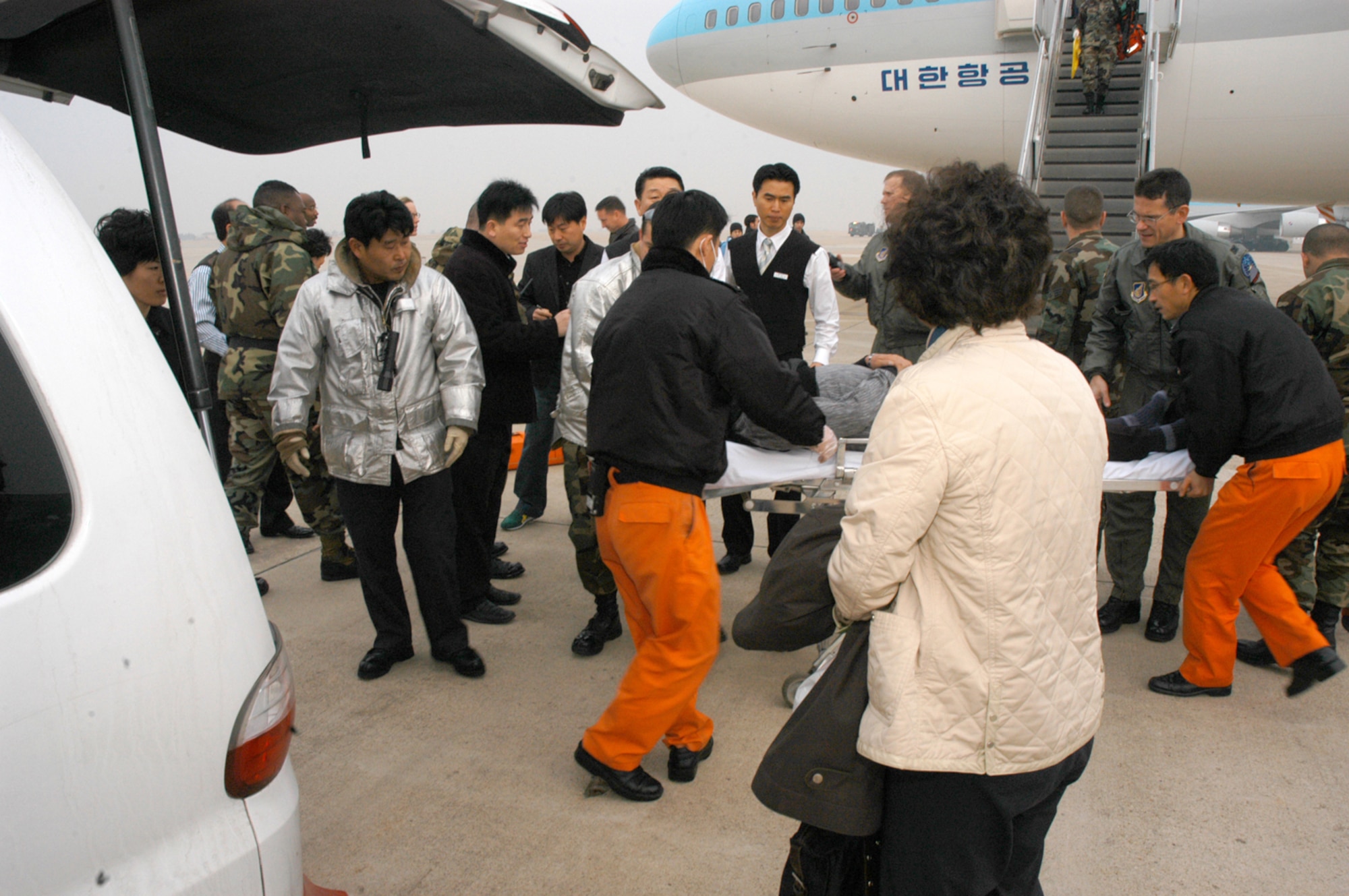 KUNSAN AIR BASE, Republic of Korea Jan. 17, 2007 -- Medical and security personnel rush a 65-year old Korean male in need of medical attention to an awaiting ambulance after his Korean Airline flight was diverted to Kunsan from Incheon International Airport. The passenger airliner, with 274 people on board, diverted here due to poor weather at Incheon. He was transported to Kunsan Medical Center, located in downtown Kunsan City. The passengers were offered bottled water as they waited to take off, and the aircraft was refueled by Air Force personnel.  (U.S. Air Force photo by Staff Sgt. Nathan Gallahan)