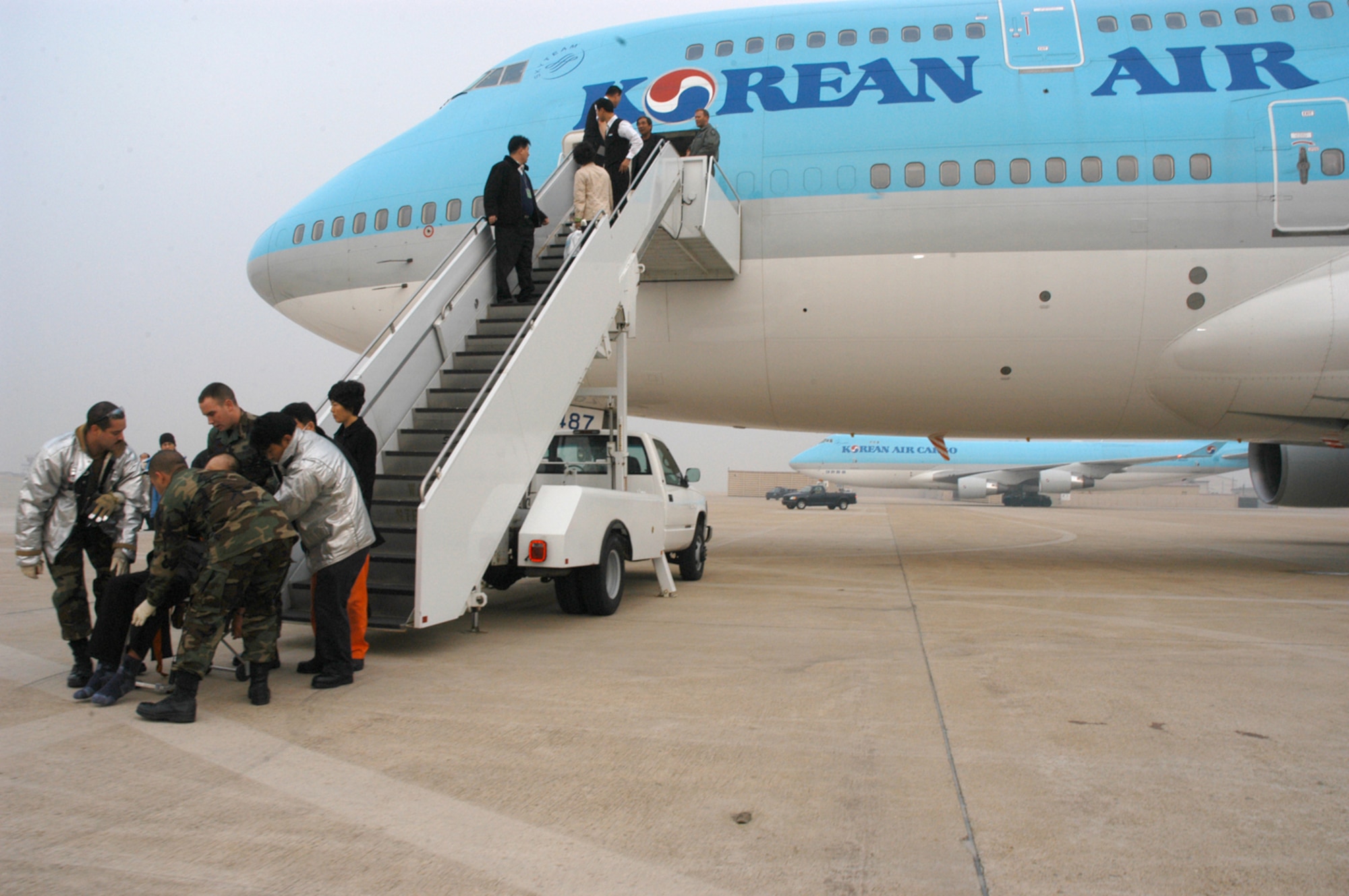 Medical and security personnel rush a 65-year old Korean man needing medical attention to an ambulance after his Korean Airline flight was diverted to Kunsan from Incheon International Airport. The passenger airliner, with 274 people on board, diverted to Kunsan because of poor weather conditions at Incheon. The Korean man was transported to Kunsan Medical Center in downtown Kunsan City. The passengers were offered bottled water as they waited to take off, and the aircraft was refueled by Air Force personnel. (U.S. Air Force photo/Staff Sgt. Nathan Gallahan) 