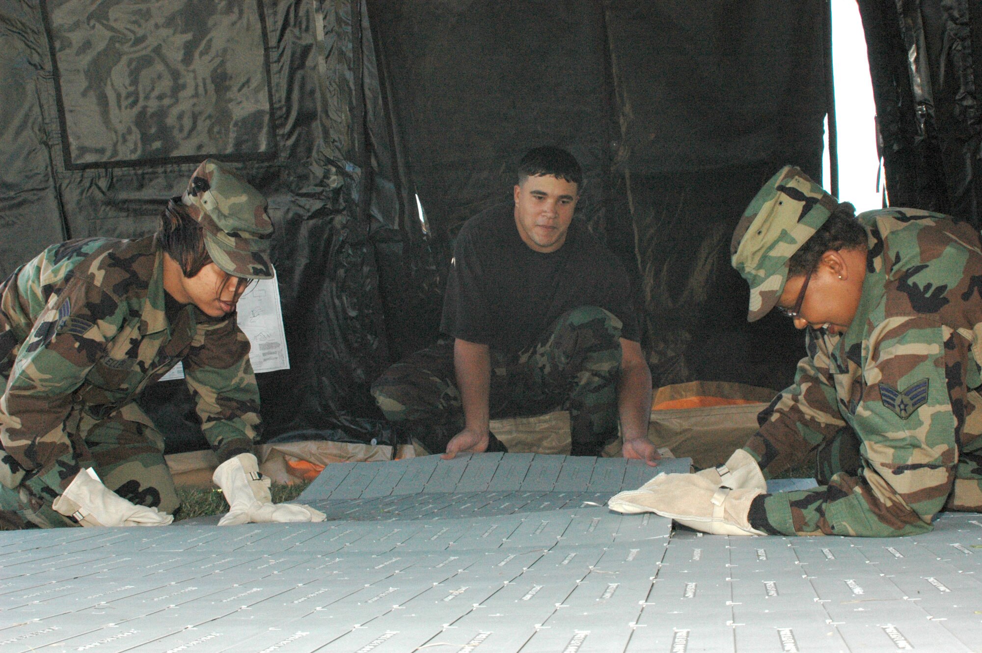 Senior Airman Ebonnie McKeller, Senior Airman Leonardo Feliu, and Senior Airman Angela Meeks-Baile set down the flooring for the 403rd Service Flight's SPEK. This new spacious, deployable kitchen takes the place of the cramped Mobile Kitchen Trailer. The SPEK can feed up to 550 people in a two-hour period which is more than double the MKT's cability. (U.S. Air Force Photo By Airman 1st Class Tabitha Spinks)