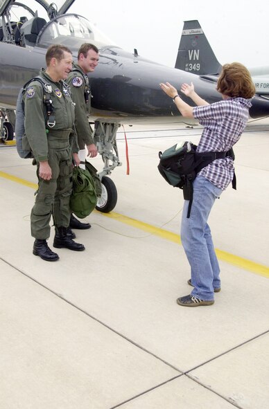 (Photo by Frank McIntyre) Roger Wiles, Lear Siegler flight instructor, and his son Capt Andrew Wiles, 25th Flying Training Squadron, are directed for a photo by Maike Rode, Enid News & Eagle photographer, July 9 after their side-by-side flight. The flight was a mandatory refresher for Roger.