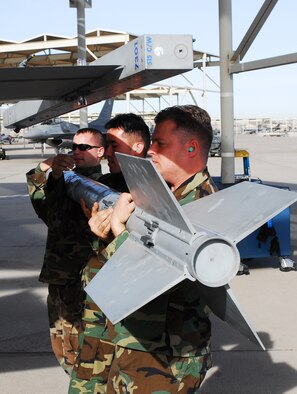 Staff Sgt. Joseph Shanks, right, Staff Sgt. Grayson Nagata, center, and Senior Airman
Matthew Raesly, 309th Aircraft Maintenance Unit weapons specialists, load an AMA podonto an F-16.