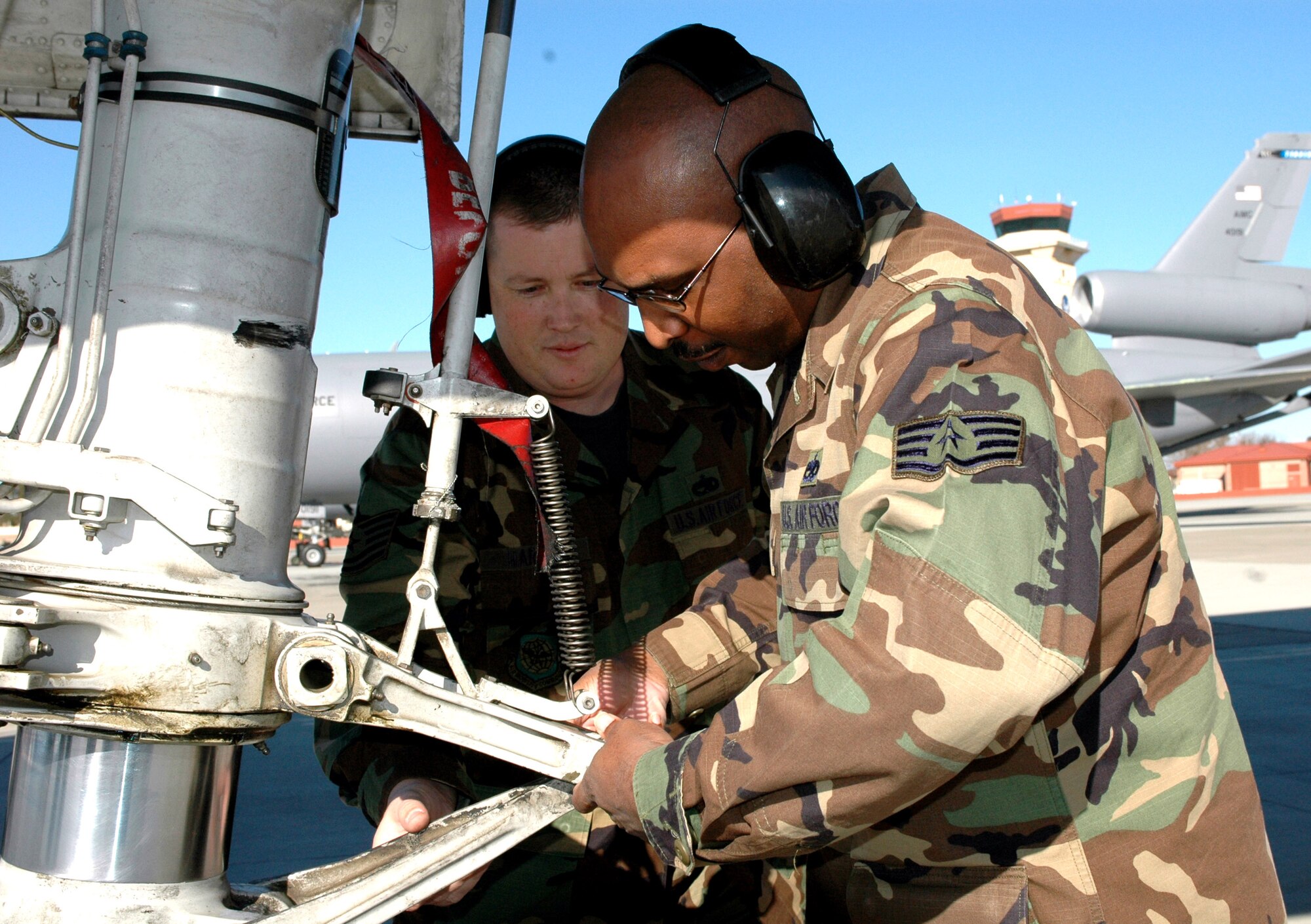 Tech. Sgt. Kevin Harding (left) shows Staff Sgt. Andre Lee how a KC-10 Extender is towed using the nose landing gear Jan. 17 at Travis Air Force Base, Calif. Sergeant Harding is assigned to the 60th Maintenance Operations Squadron at Travis AFB, and Sergeant Lee is from the 735th Aircraft Maintenance Squadron, Hickam Air Force Base, Hawaii.  Sergeant Lee is part of the 60th MOS two-phase, training program designed to help streamline KC-10 maintenance. (U.S. Air Force photo/Staff Sgt. Candy Knight) 
