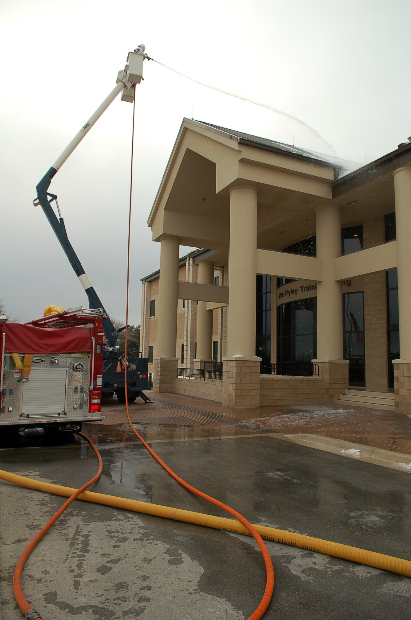 Airman Nicholas Powanda, Laughlin fire department, sprays snow and ice from the roof of the 47th Flying Training Wing headquarters building Thursday.  Since snow and ice are unusual this far south, most buildings in the area are not equipped with protective measures to keep heavy snow from falling off roofs onto walkways and entryways.  The fire department was called to help remove these hazards once they began melting, causing them to fall. (U.S. Air Force photo by Staff Sgt. Austin May)
