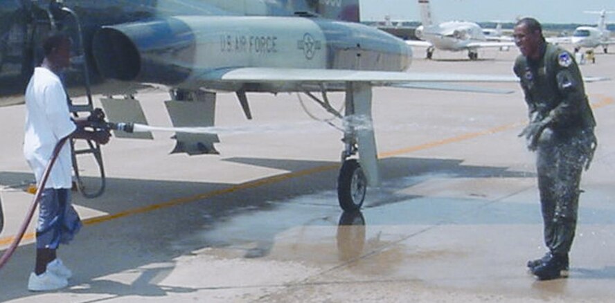 (Photo by John Ray) Col Jim Calhoun receives a wet reception from his son Michael following the colonel’s fini flight last month.