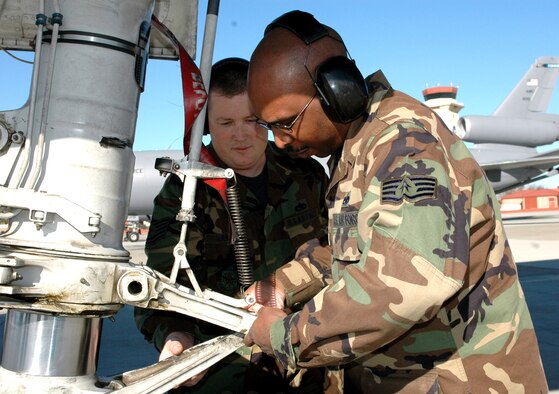 Tech. Sgt. Kevin Harding, (left), 60th Maintenance Operations Squadron, shows Staff Sgt. Andre Lee, 735th Aircraft Maintenance Squadron, Hickam Air Force Base, Hawaii, how a KC-10 aircraft is towed using the nose landing gear. Sergeant Lee is part of the 60th MOS two-phase, training program designed to help streamline KC-10 maintenance. (U.S. Air Force photo by Staff Sgt. Candy Knight)