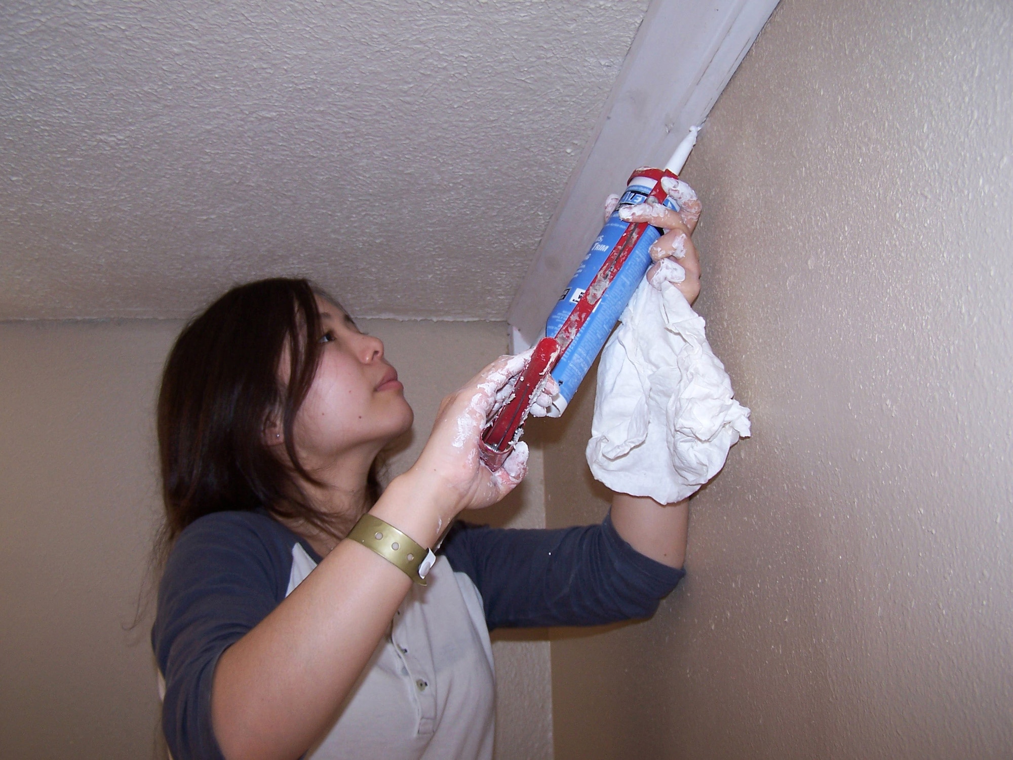 Senior Airman Thy Hoang applies caulking to wood trim in a home being restored in Bay St. Louis, Miss. The home was damaged by Hurricane Katrina more than a year ago. Airman Hoang is a 354th Medical Support Squadron pharmacy technician from Eielson Air Force Base, Alaska. She was one of five Airmen who travelled from Eielson AFB to the Gulf coast to repair Hurricane Katrina-damaged homes. (U.S. Air Force photo/Senior Airman Anthony Nelson)