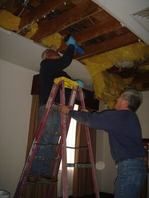 Alex Barcelona, (on the ladder) and Benjamin Cerrillo, both from the 95th Civil Engineer and Transportation Directorate, repair a broken water line in a temporary living facility Wednesday. The water pipe broke during extra-cold temperatures in the area last week. As of Tuesday, civil engineers received more than 306 calls about frozen pipes, flooding or structural damage. (Photo by Gerald Boetsch)
