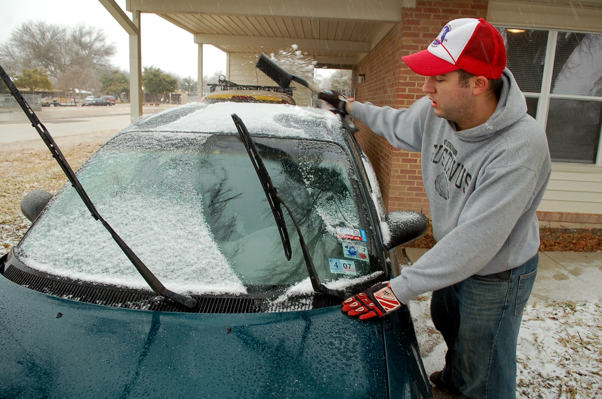 LAUGHLIN AIR FORCE BASE, Texas -- Airman 1st Class Justin Roberts, 47th Maintenance Directorate Precision Engineering and Maintenance Lab, brushes snow off the windshield of his car after a light dusting early Tuesday.  (U.S. Air Force photo by Staff Sgt. Austin May)

