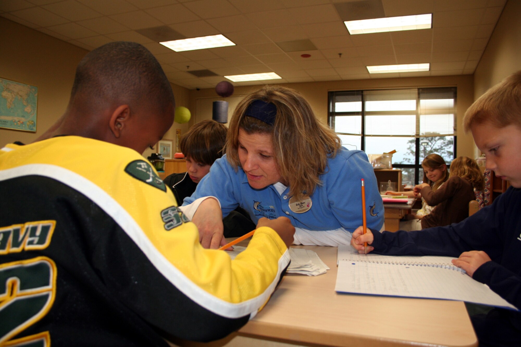 Kathy Moore helps children with their homework during the power hour at the Youth Center. (U.S. Air Force Photograph by Dylan Laurie)
