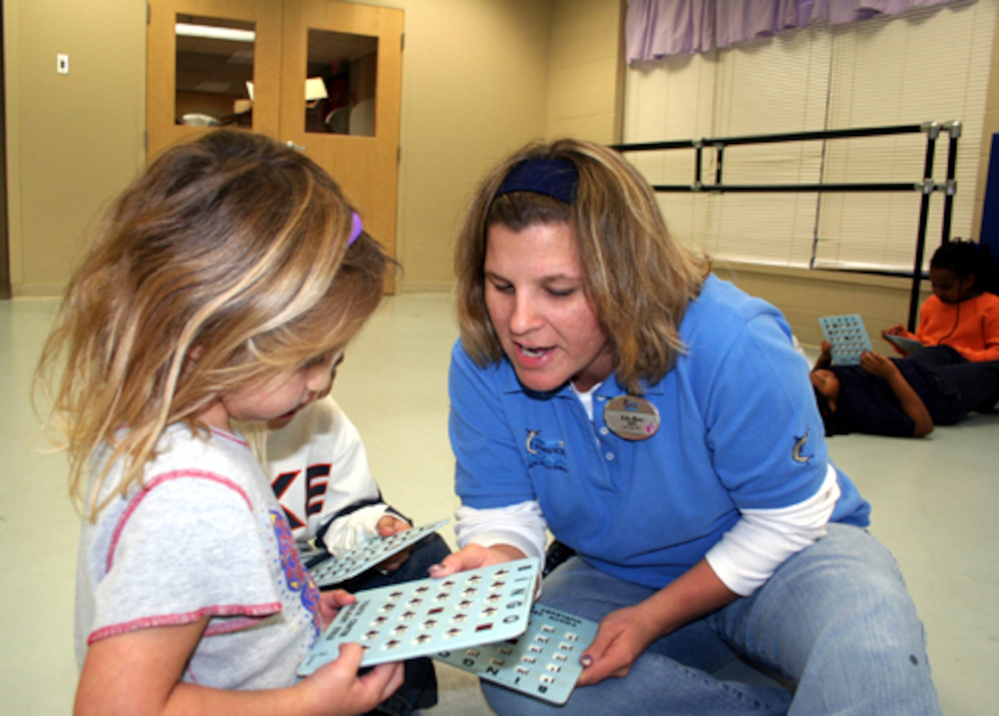 Kathy Moore helps children with their homework during the power hour at the Youth Center. (U.S. Air Force Photograph by Dylan Laurie)