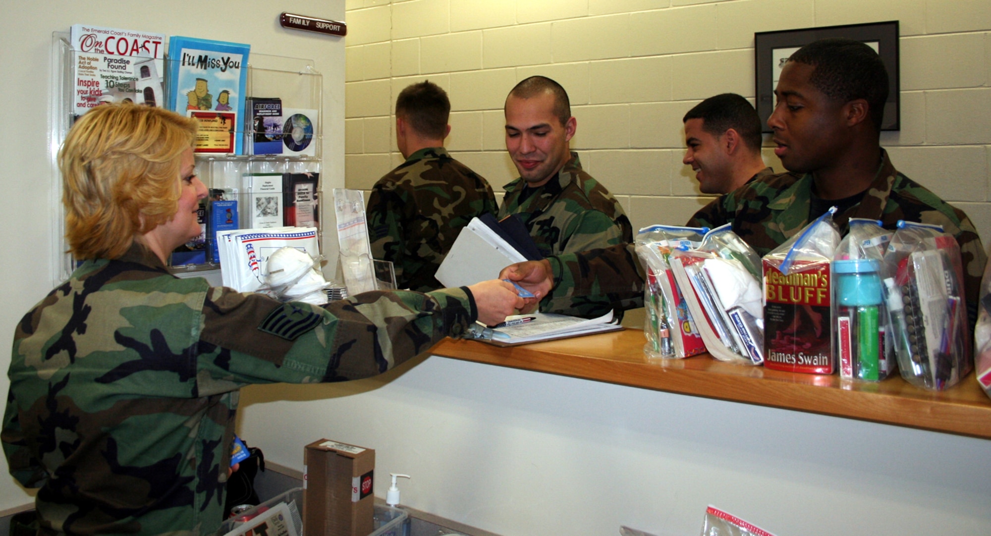 Technical Sgt. Diane Thomas, left, 1st Special Operations Mission Support Squadron personal and family readiness NCO, hands out phone cards to Airmen at the Deployment Control Center. (U.S. Air Force Photograph by Dylan Laurie)