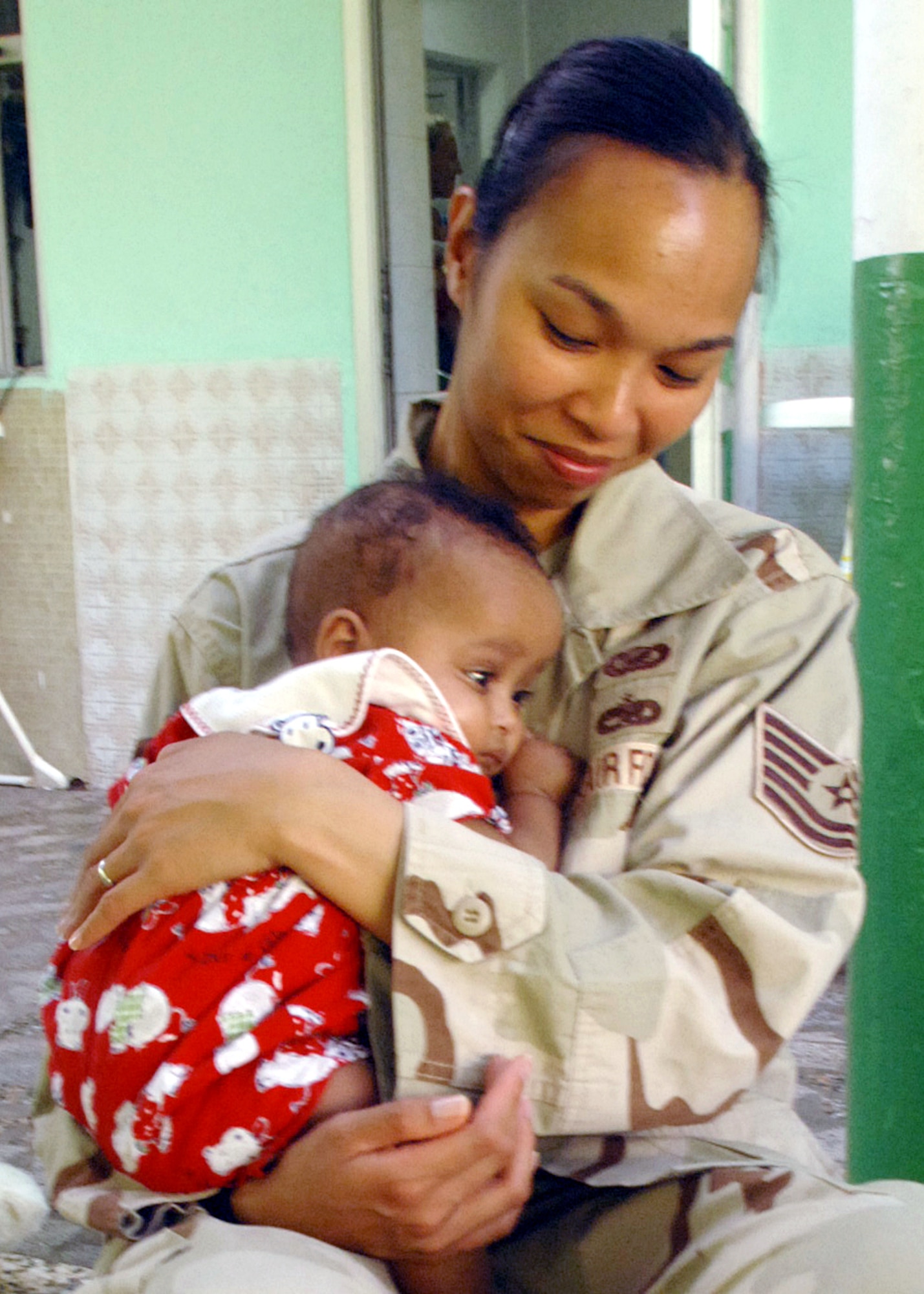 Tech. Sgt. Renee Crisostomo comforts an orphaned baby at the Franciscan Missionaries of Notre Dame Baby Orphanage in Djibouti City, Djibouti. Sergeant Crisostomo, a broadcaster on the U.S. Central Command Air Forces News Team, was on assignment to feature Airmen supporting the Combined Joint Task Force - Horn of Africa at Camp Lemonier, Djibouti, when she paused filming and volunteered at the orphanage. The Camp Lemonier chapel staff arranges visits to this orphanage three times a week. (U.S. Air Force photo/Staff Sgt. Francesca Popp)