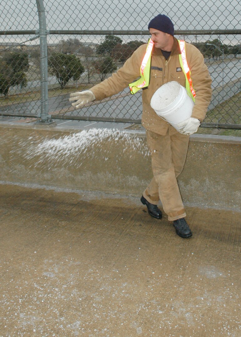 A Lackland Air Force Base civil engineering worker spreads rock salt on an icy sidewalk on the Truemper Street bridge over Military Drive the morning of Jan. 17. The winter storm that started Jan. 15 blanketed San Antonio and the surrounding Hill Country, knocking out power for many and making travel nearly impossible. Lackland Air Force Base was one of many military bases and businesses closed Jan. 16 and 17. (USAF photo by Alan Boedeker)                                