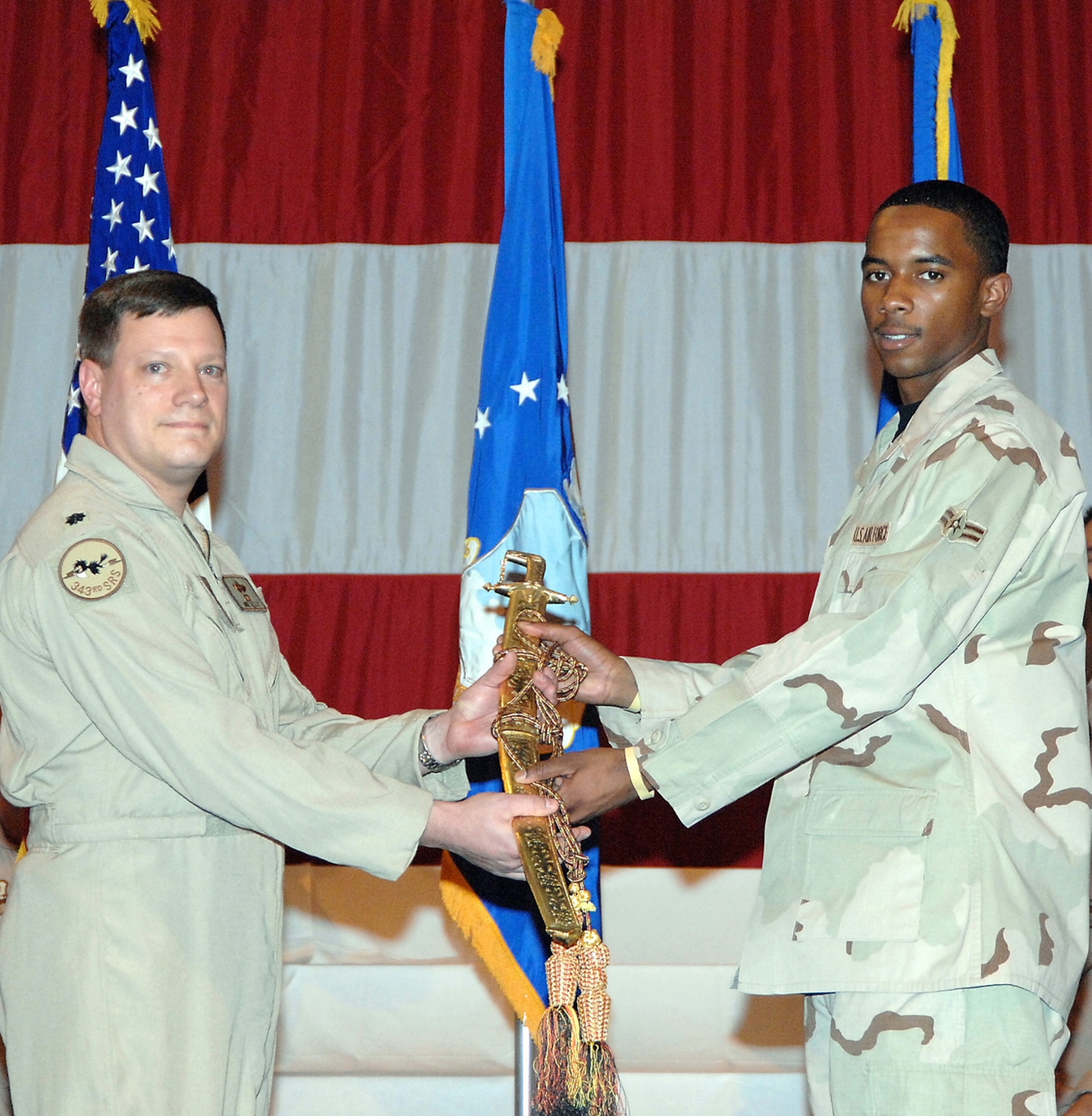 Lt. Col. Michael Kelly, 338th Combat Training Squadron director of operations, passes a sword symbolizing the 55th Wing’s changing of the guard to Airman 1st Class Gary Chappell, the youngest Airman to return from the Wing’s latest deployment. U.S. Air Force Photo by Daniel J. Rohan Jr.